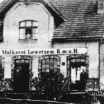 Mleczarnia, znajdowała się na wschodnim krańcu wsi. Istniała od 1907 do 1938. W górnym oknie Hedwig Duske (z d. Jeske). W lewych drzwiach stoi Ernst Duske, a w prawych drzwiach jego praktykant, Henschel, 1926